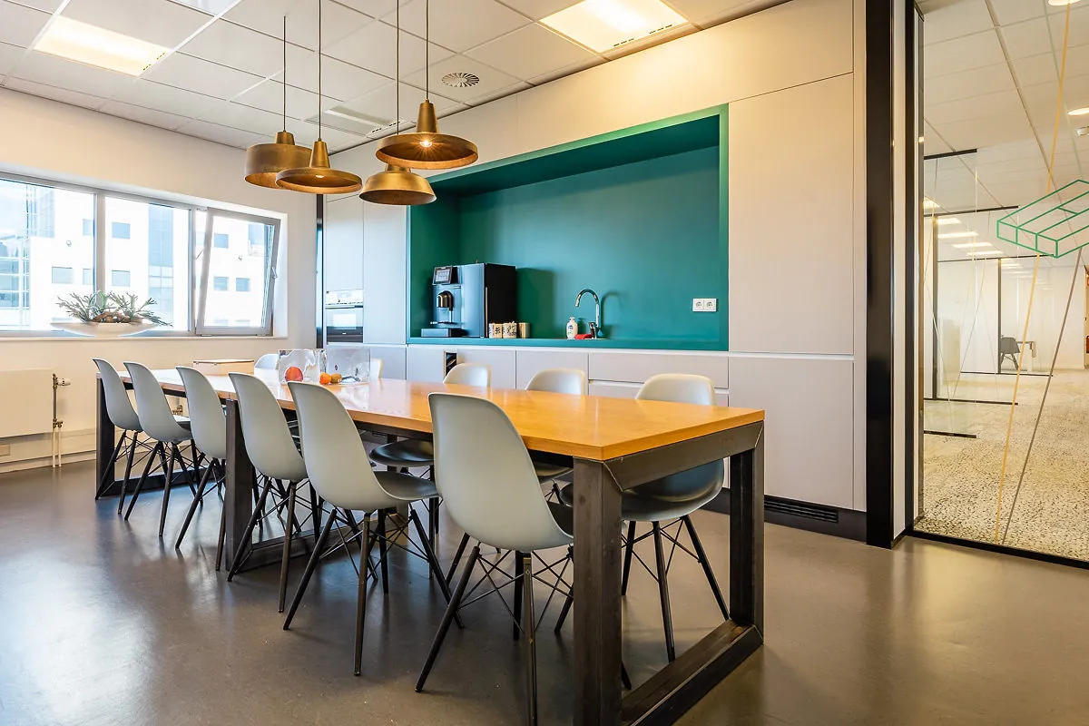 Moderne kantoorkeuken in Rivium Quadrant met lange houten eettafel, designstoelen en een koffiecorner.